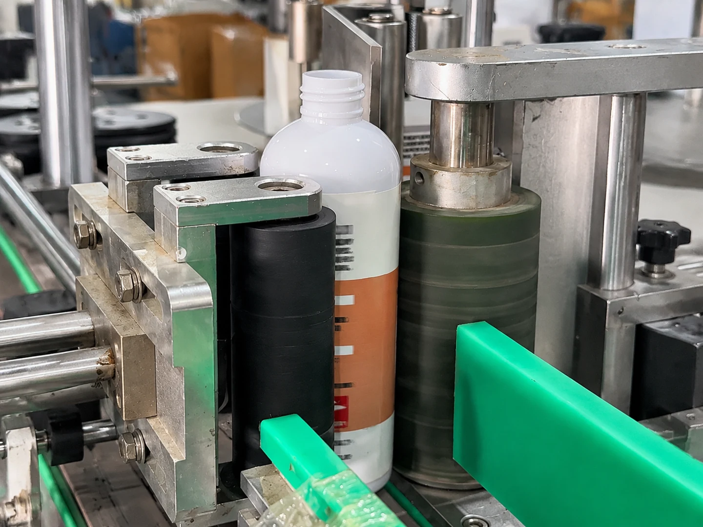 White product bottle passing between labeling machine rollers and guides