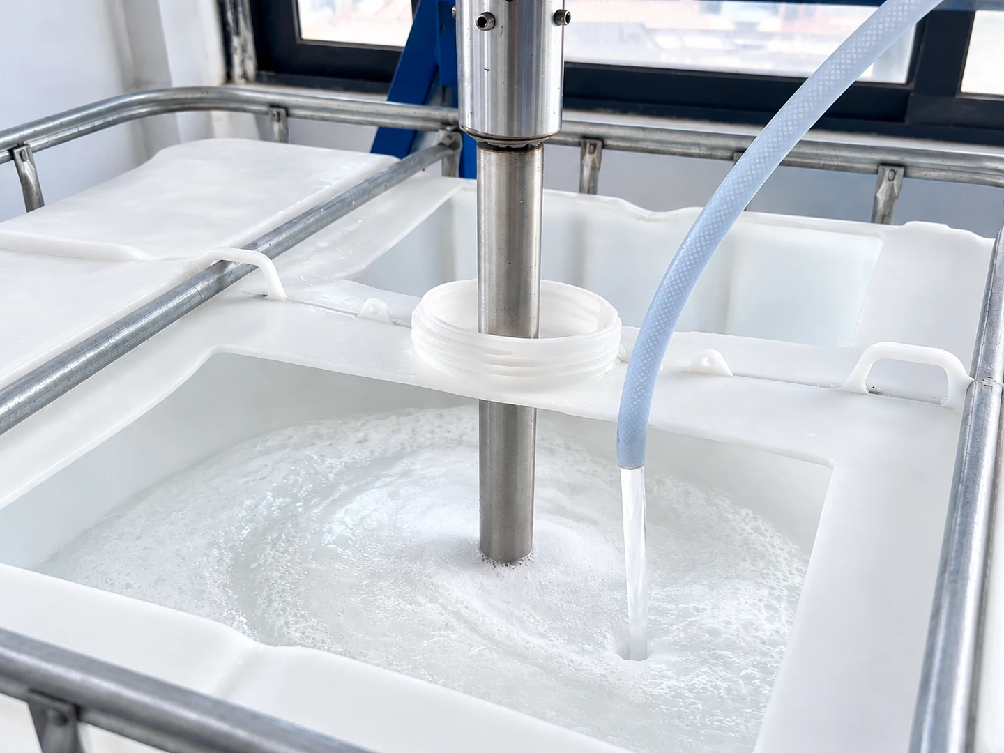 Mixing shaft and feed hose positioned in a production vessel containing liquid